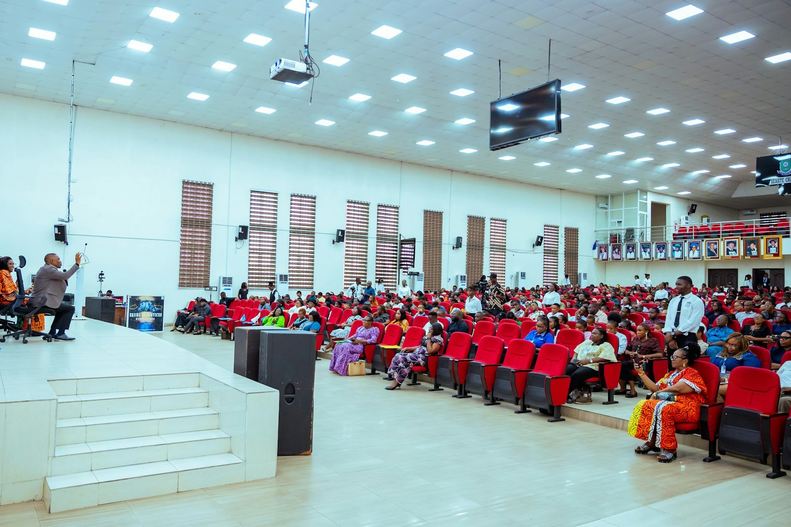 Audience seated in a large hall with a stage