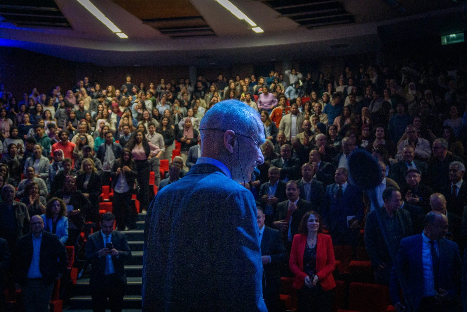 Speaker addressing a large audience in a theater.